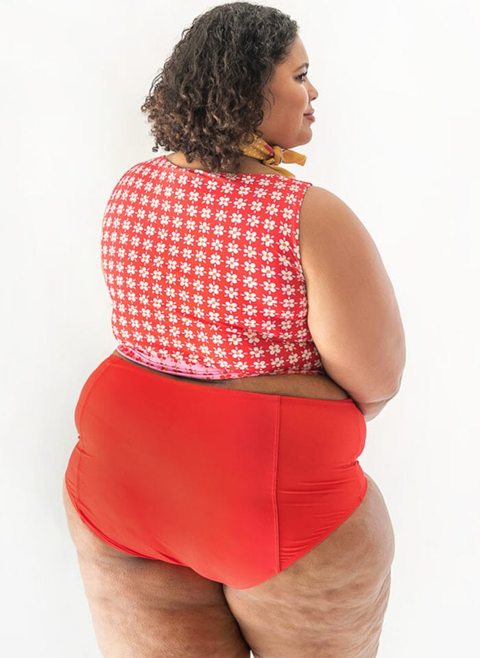 Photo of a woman wearing a red swim bottom and a red floral swim crop top back angle