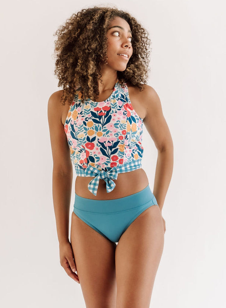 Photo of a woman wearing a May Flowers cross-back swim crop top and a blue swim bottom