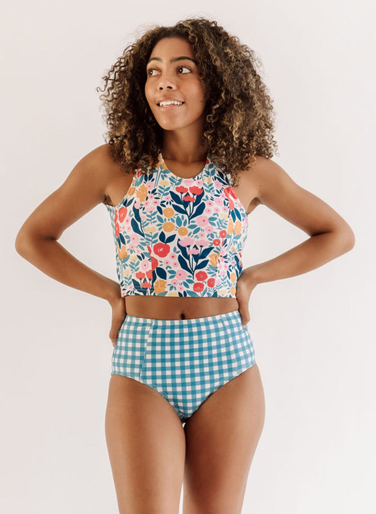 Photo of a woman wearing a May Flowers cross-back swim crop top and a blue and white checkered swim bottom