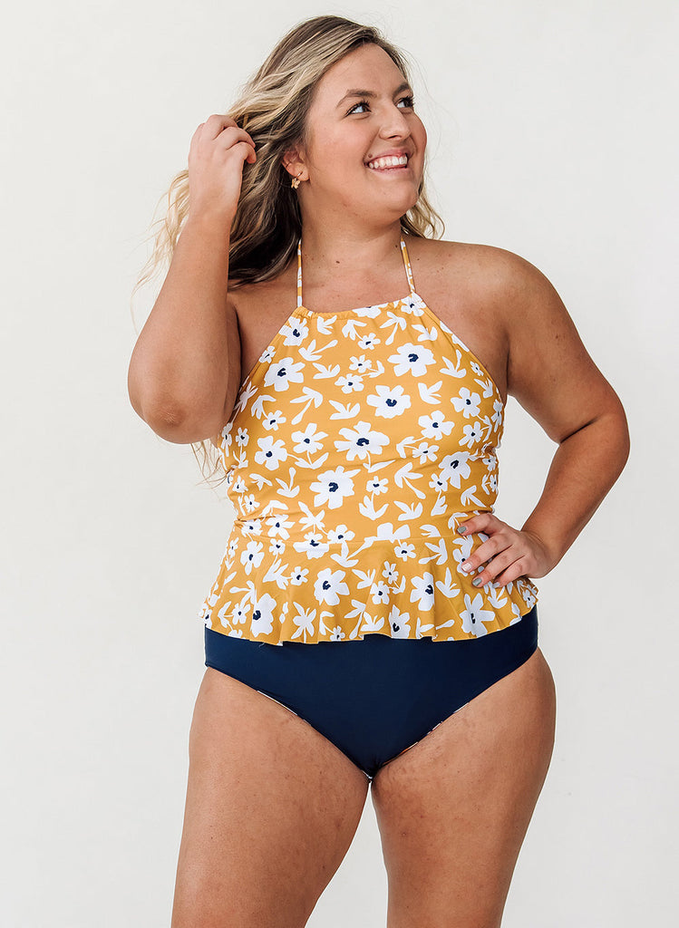 Photo of woman wearing yellow floral swim top with blue swim bottoms