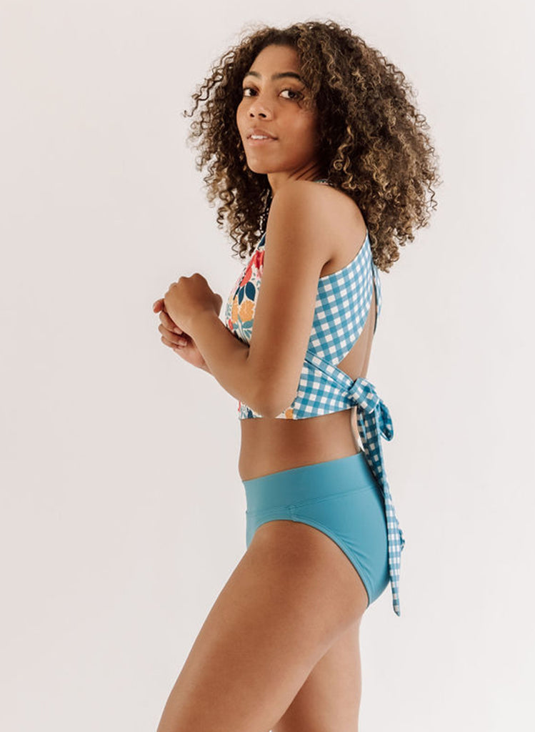 Photo of a woman wearing an Ocean classic swim bottom and a May Flowers swim crop top side angle