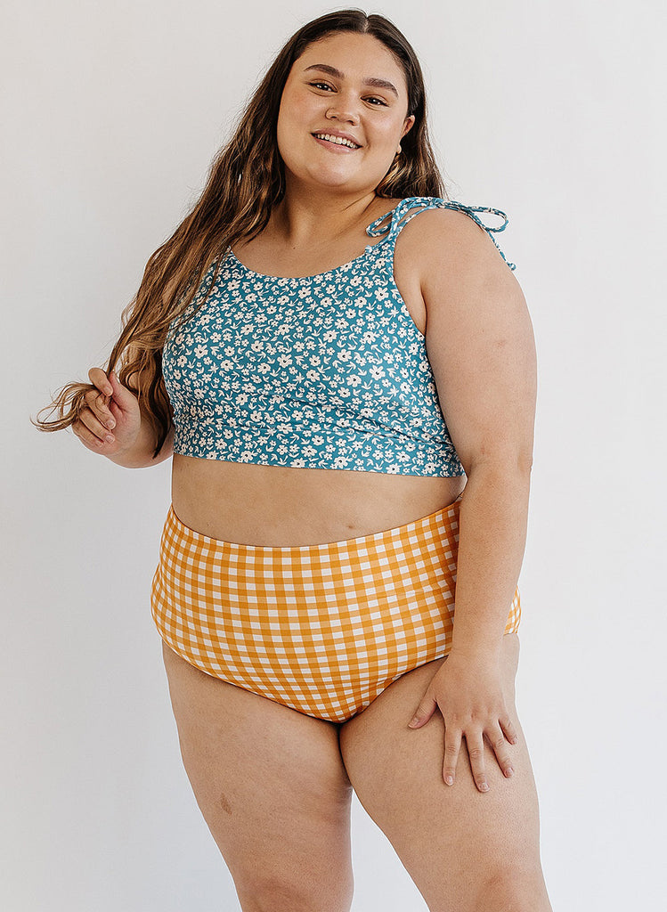 Photo of woman wearing blue floral cropped swim top with yellow and white gingham swim bottoms