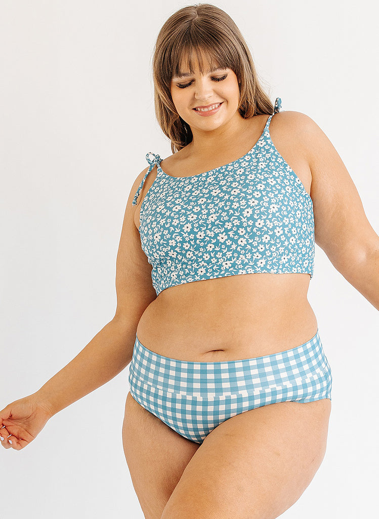 Photo of woman wearing blue floral cropped swim top with blue and white gingham swim bottoms