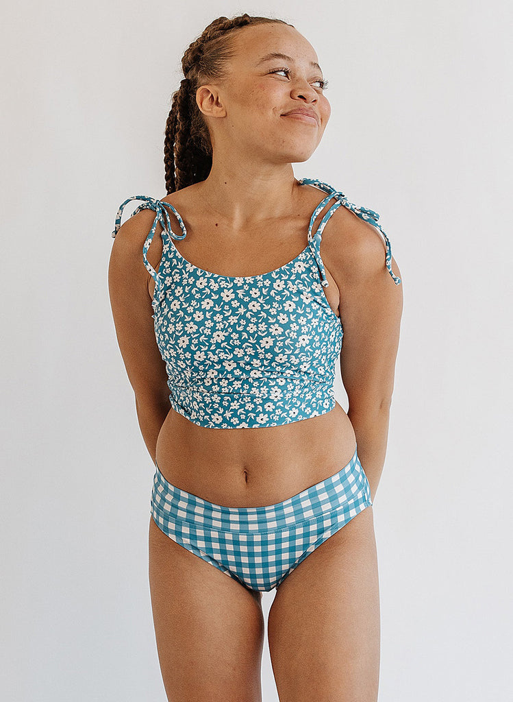 Photo of woman wearing blue floral cropped swim top with blue and white gingham swim bottoms