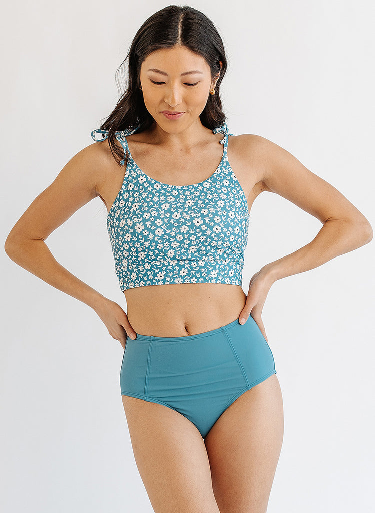 Photo of woman wearing blue floral cropped swim top with blue swim bottoms