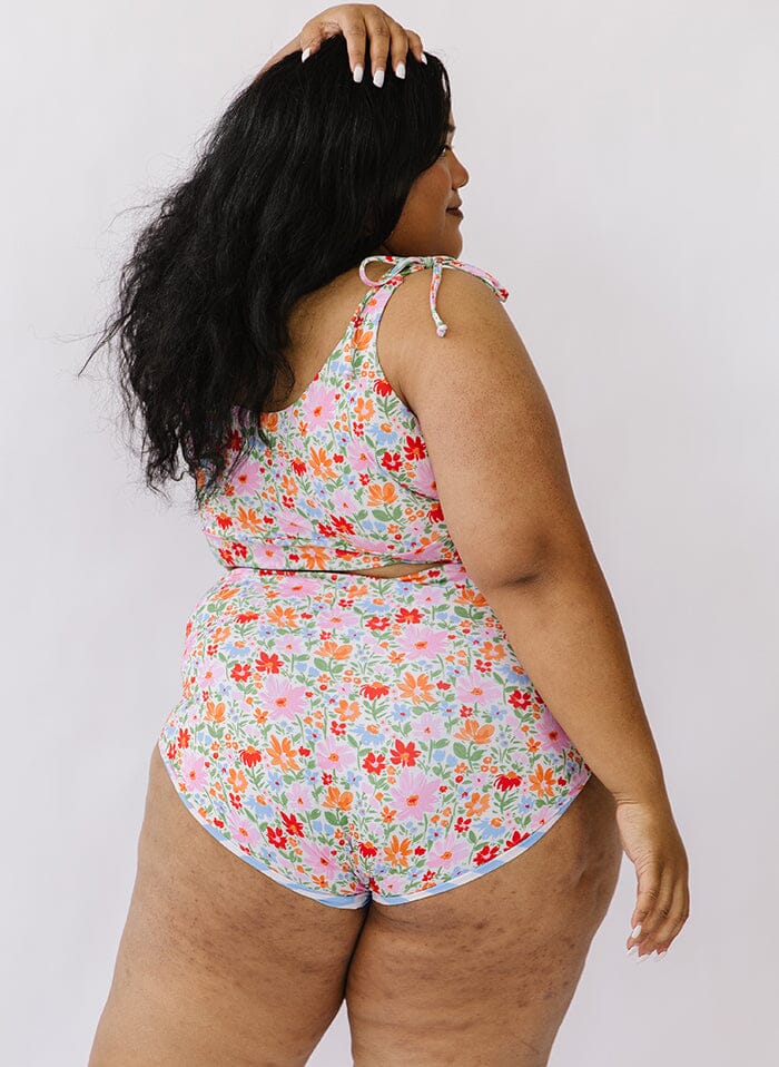 Photo of a woman wearing a floral shoulder-tie swim crop top and a floral swim bottom back angle