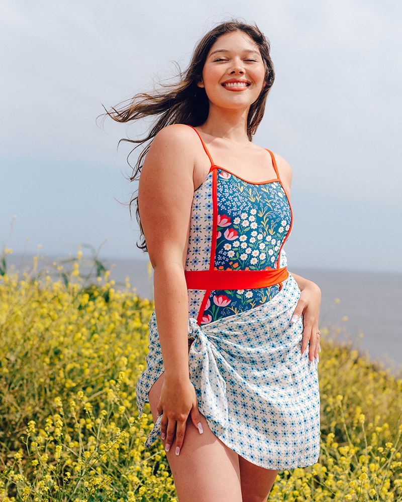Photo of a woman wearing a light blue floral sarong and a multi color floral swim suit