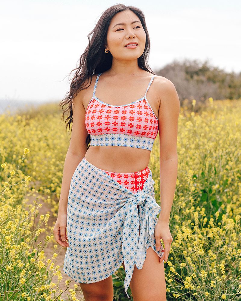 Photo of a woman wearing a light blue floral sarong and a multi color floral swim bralette