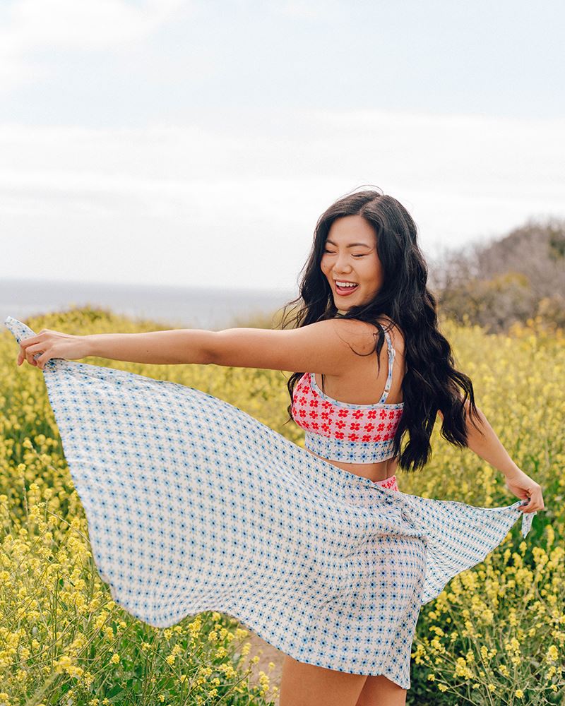Photo of a woman wearing a light blue floral sarong and a multi color floral swim bralette side angle
