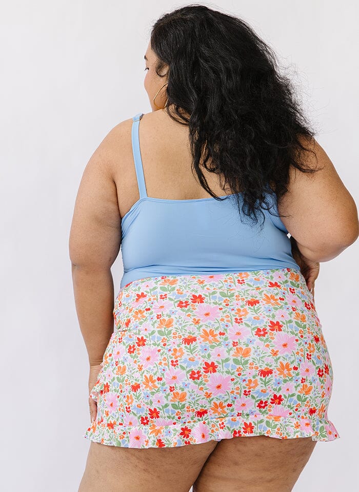 Photo of a woman wearing a peri square neck swim top and a floral swim skirt bottom back angle