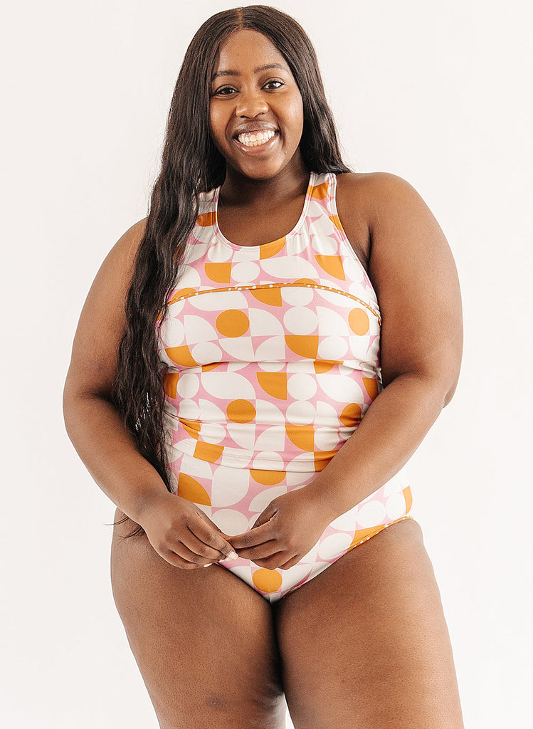 Photo of woman wearing orange and white geometric swim top with orange and white geometric swim bottoms