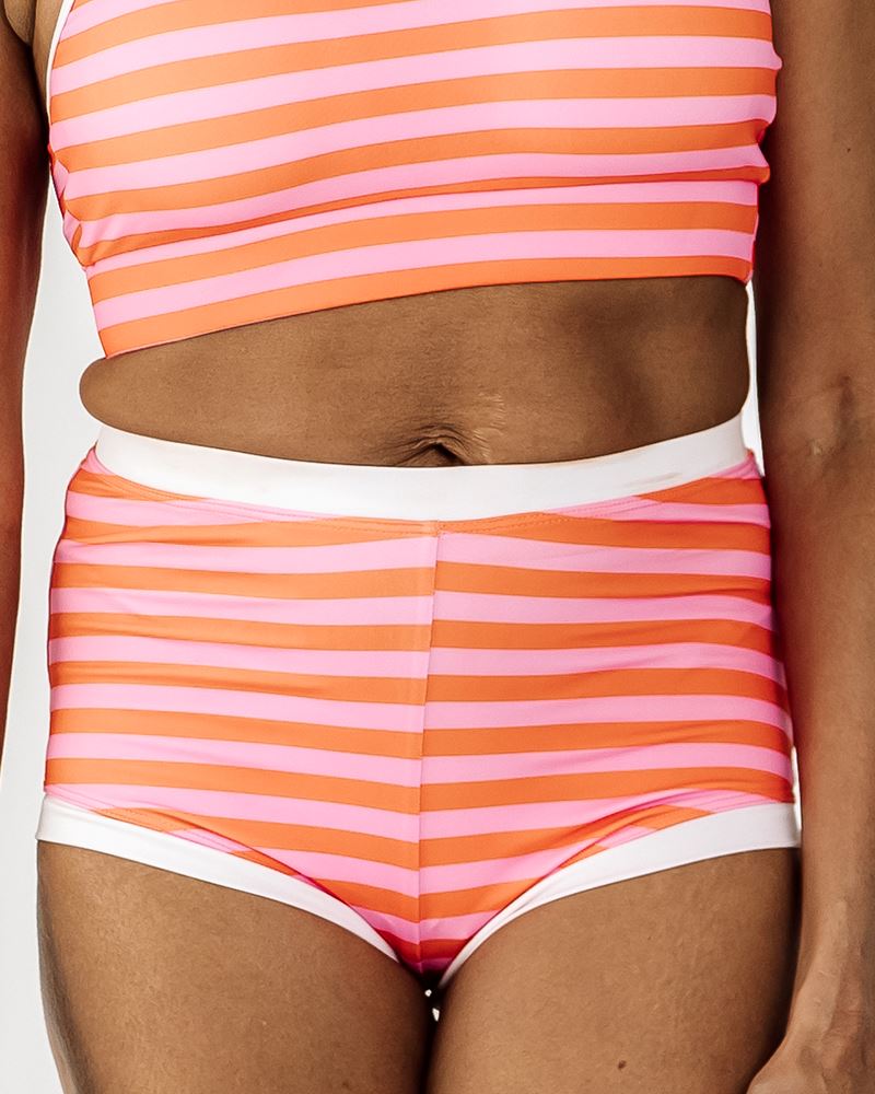 Photo of a woman wearing a Sherbet stripe retro swim short bottom and a Sherbet stripe swim crop top