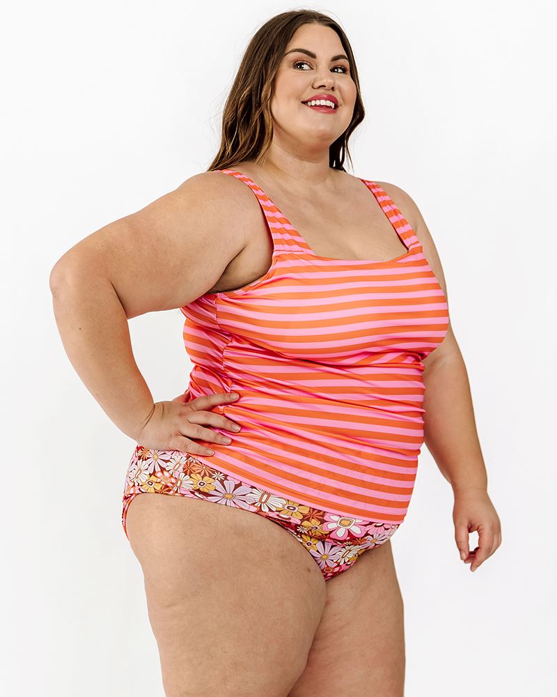 Photo of a woman wearing a Sherbet stripe square neck swim top and a Groovy Blooms floral swim bottom side angle