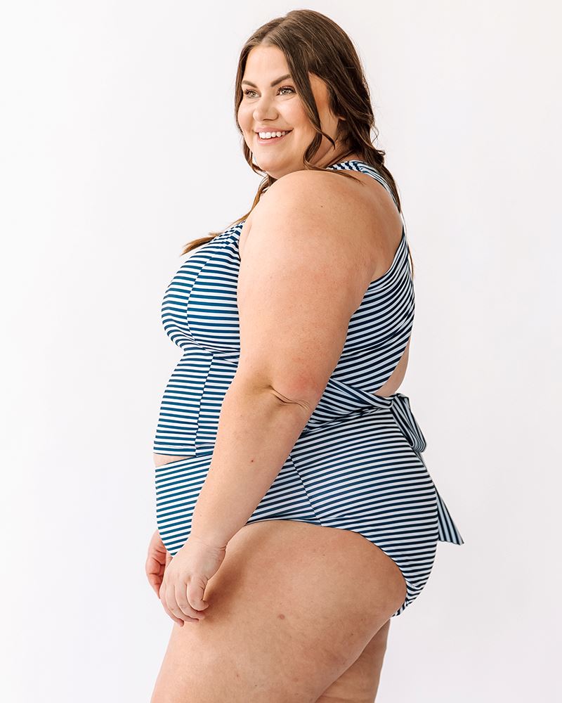 Photo of a woman wearing a June floral/ Indigo stripe reversible swim bottom stripe side and an Indigo stripe swim crop top side angle