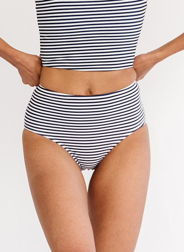 Close up photo of woman wearing a blue and white striped cropped swim top with blue and white striped high waist swim bottoms