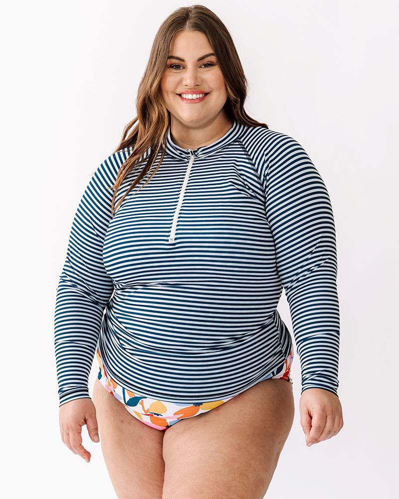 Photo of a woman wearing an Indigo stripe rash guard swim top and a multi color floral swim bottom