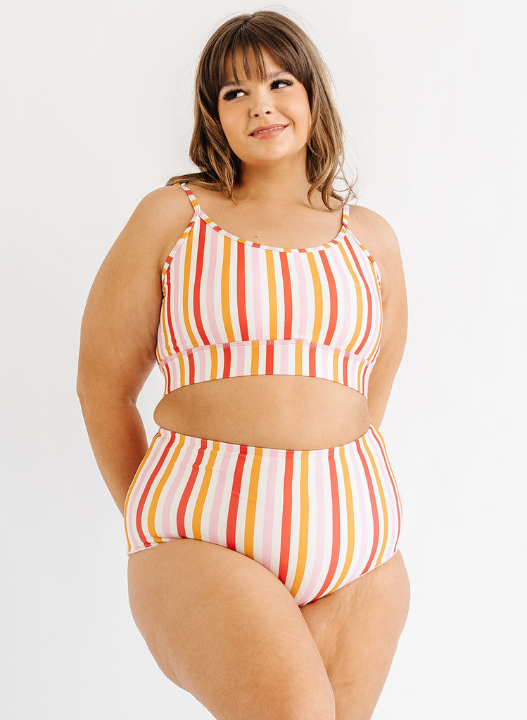 Photo of woman wearing multi color stripe bralette swim top with multi color stripe swim bottoms