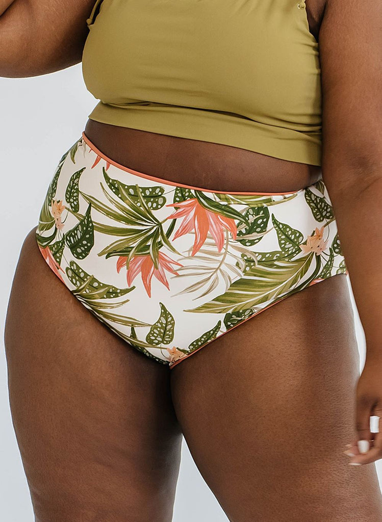 Photo of a woman wearing a cactus green swim crop top and a tropical floral swim bottom