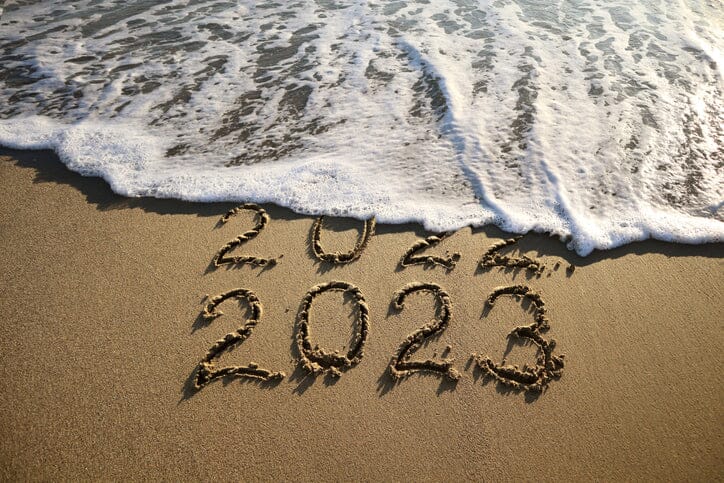 2023 written in sand ocean wave washing away 2022