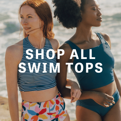 Photo of two women linking arms at the beach one wearing a blue and white striped cropped swim top with multi colored floral high waist swim bottoms the other wearing a blue cropped swim top with blue classic low rise swim bottoms
