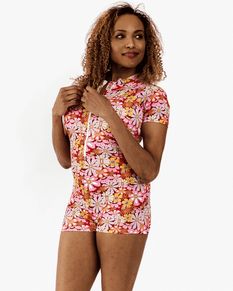 Gif of a woman wearing a groovy Blooms floral rash guard one-piece swim suit