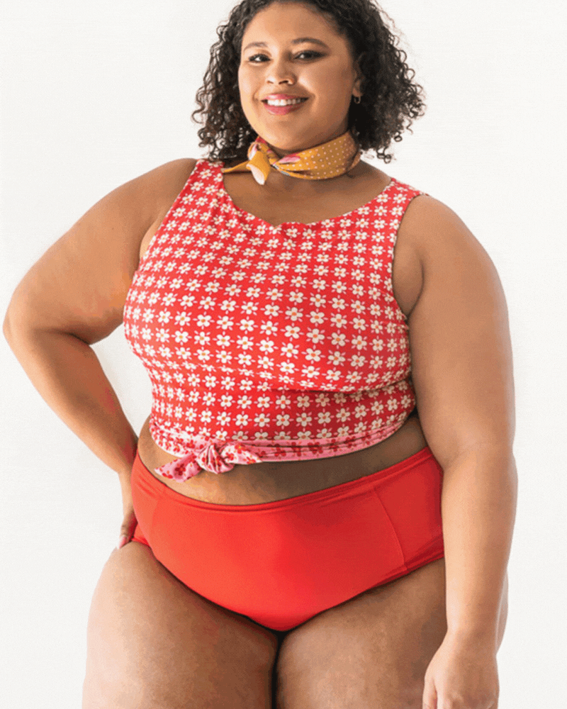 GIF of a woman wearing a red and white floral swim crop top and a red swim bottom