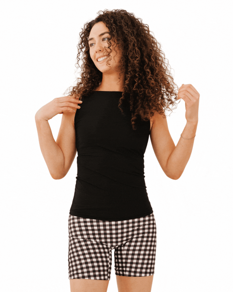 GIF of a woman wearing a black boat neck swim top and black gingham bike shorts