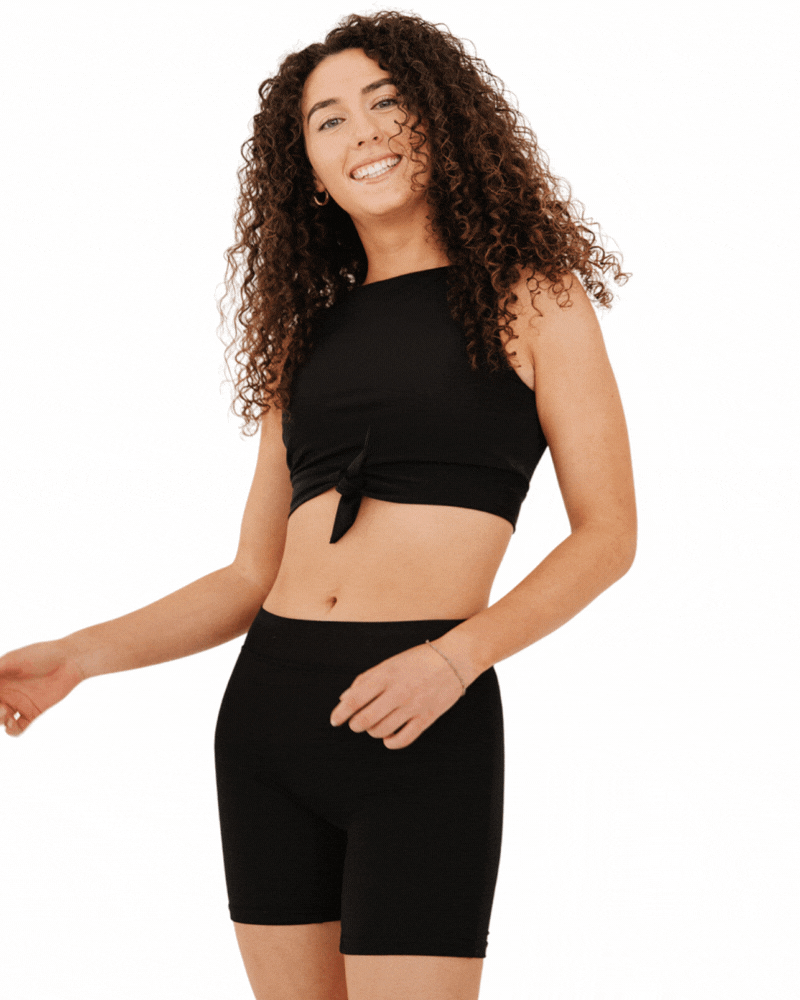 GIF of a woman wearing a black knotted swim crop top with black swim boy shorts