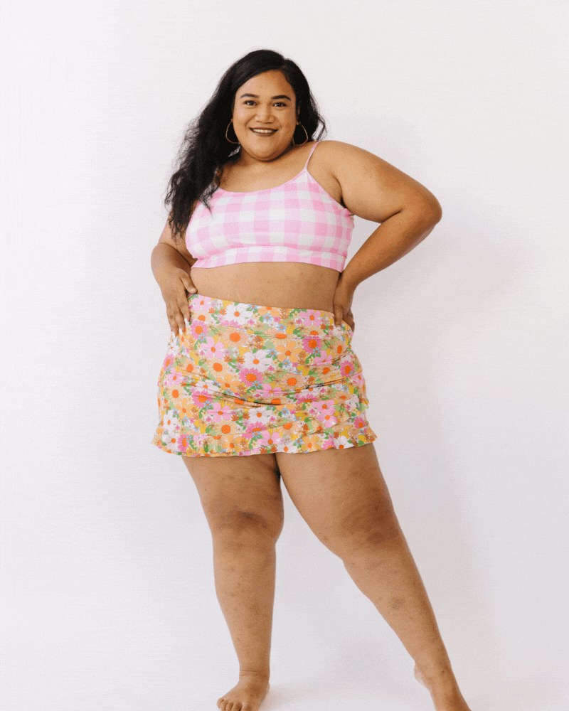 GIF of woman wearing pink gingham bralette swim top with multi colored floral swim skirt