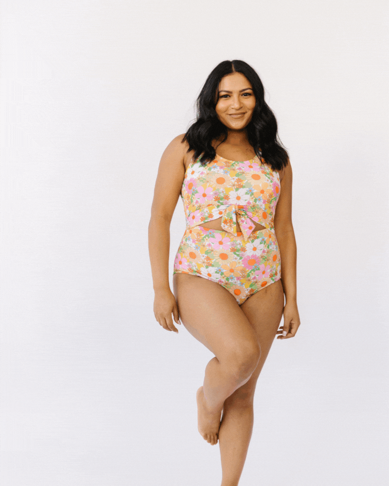 GIF of woman wearing multi colored floral knotted swim one piece