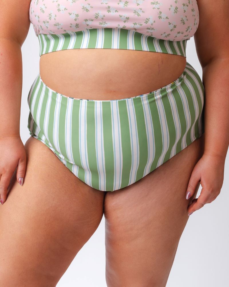 Close up photo of a woman wearing green and white striped high waist swim bottoms