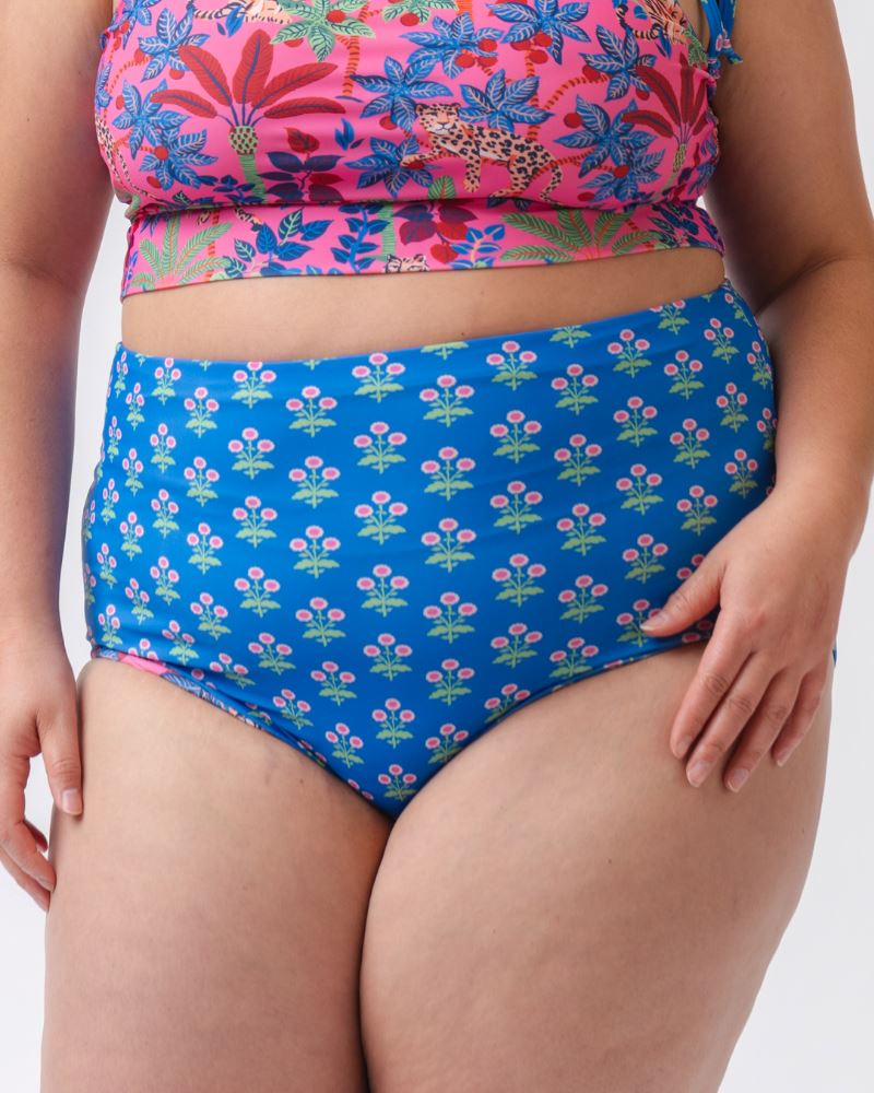 Close up photo of a woman wearing a bold pink print featuring tigers/ blue and pink floral reversible ultra high waist swim bottoms- floral side