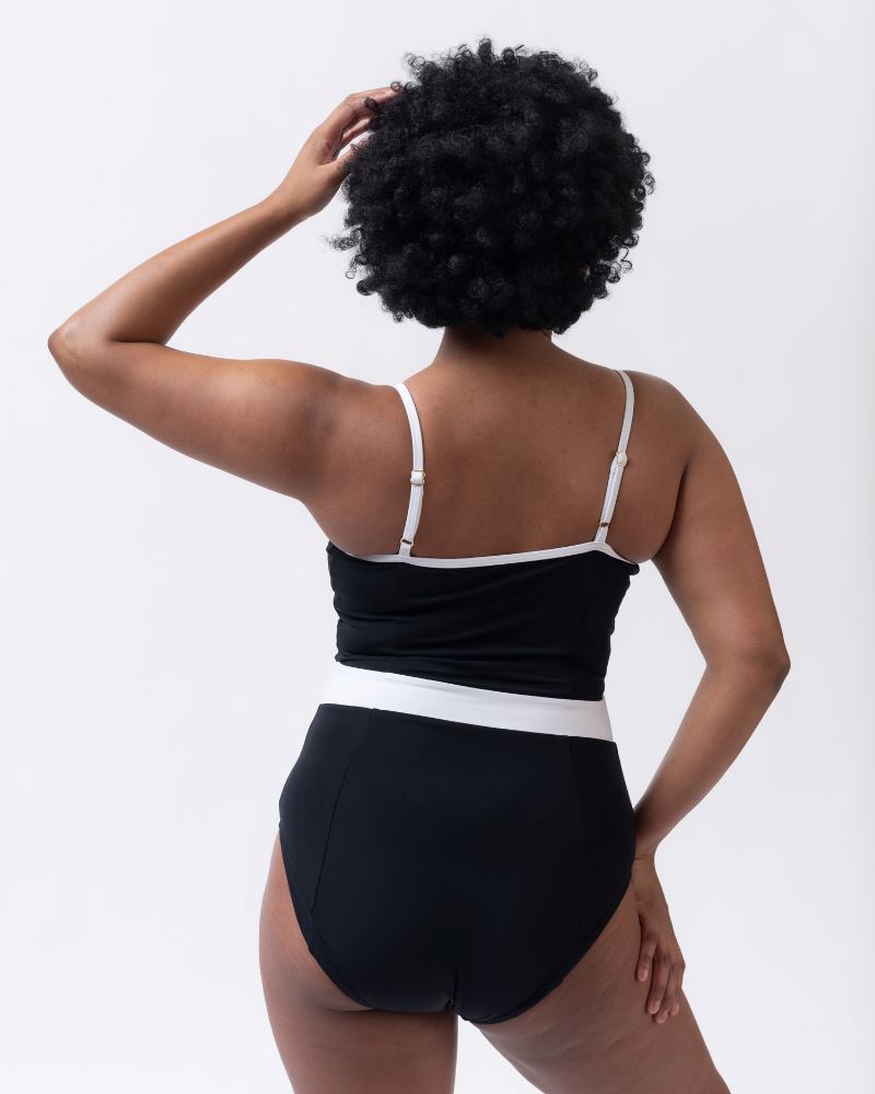 Photo of woman with her back facing us wearing a black and white classic one piece swim suit