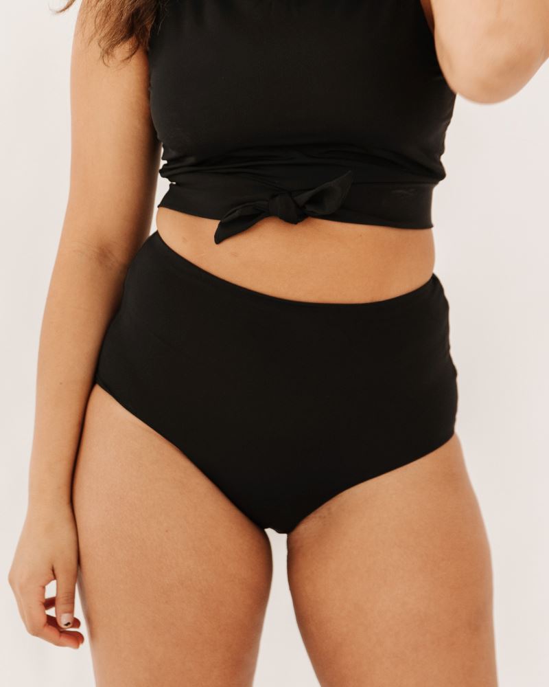 Photo of woman wearing black cropped swim top with black high waist swim bottoms