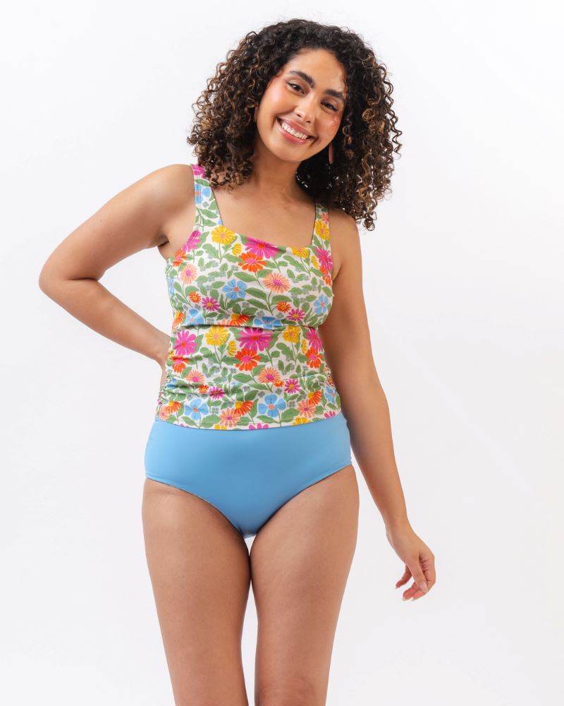 Photo of a woman wearing a multi colored floral swim tankini top with light blue high waist swim bottoms