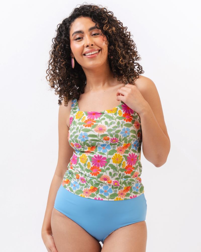 Photo of a woman wearing a multi colored floral swim tankini top with light blue high waist swim bottoms