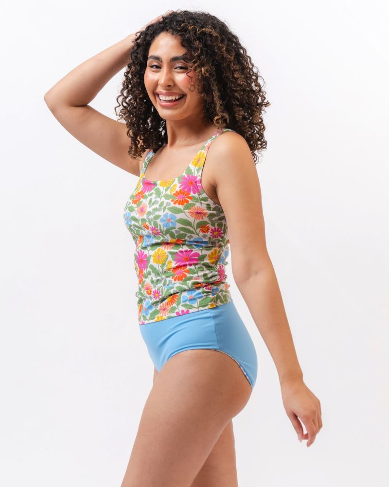 Photo of a woman from the side wearing a multi colored floral swim tankini top with light blue high waist swim bottoms