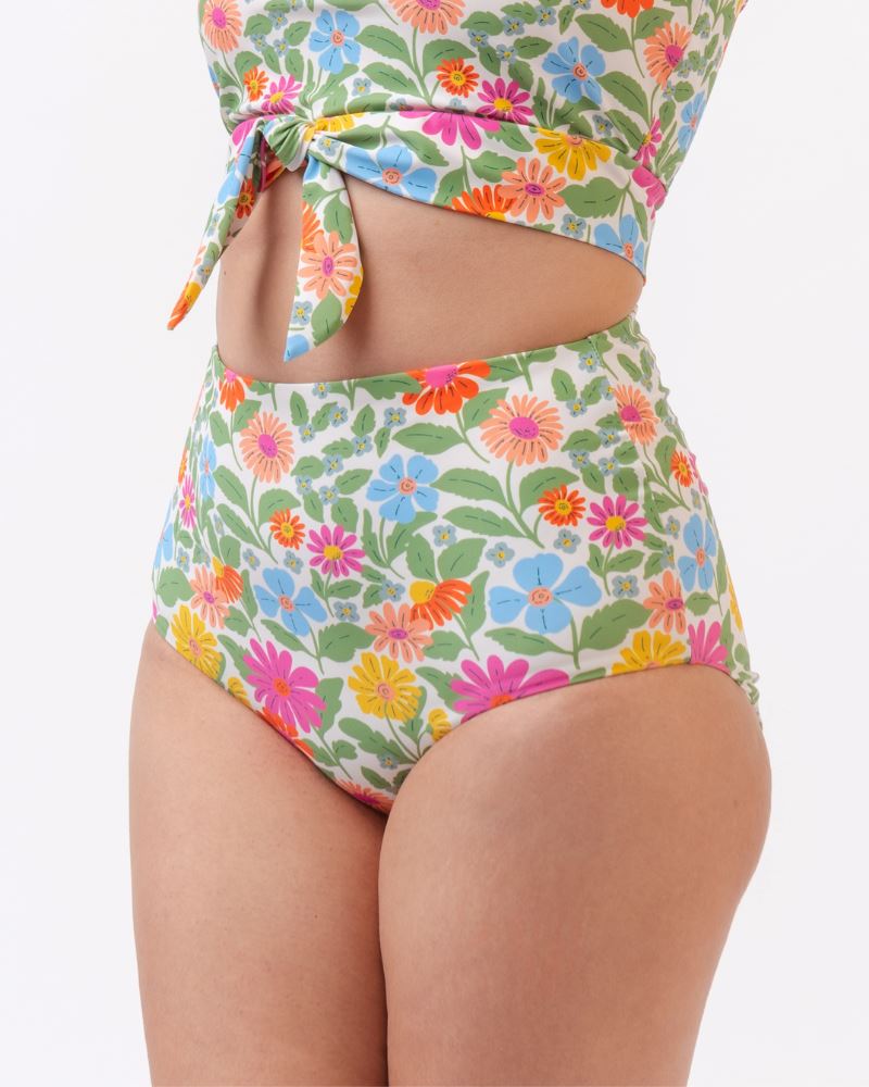 Close up photo of a woman wearing a multi colored floral cropped swim top with multi colored floral high waist swim bottoms