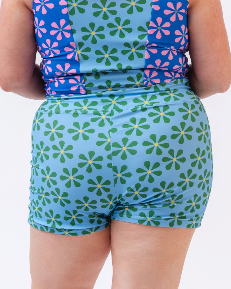 Close-up photo of a woman wearing a blue and green floral swim short bottom- back angle