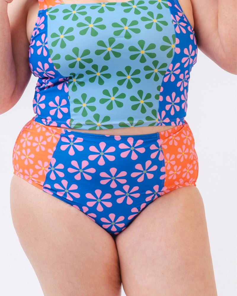 Close-up photo of a woman wearing a multi-colored floral high-waist swim bottom and a multi-colored floral swim crop top