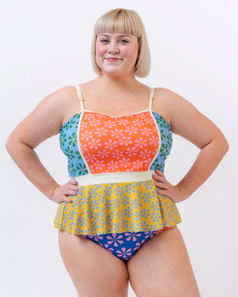 Photo of a woman wearing a multi-colored floral peplum swim top and a multi-colored floral swim bottom