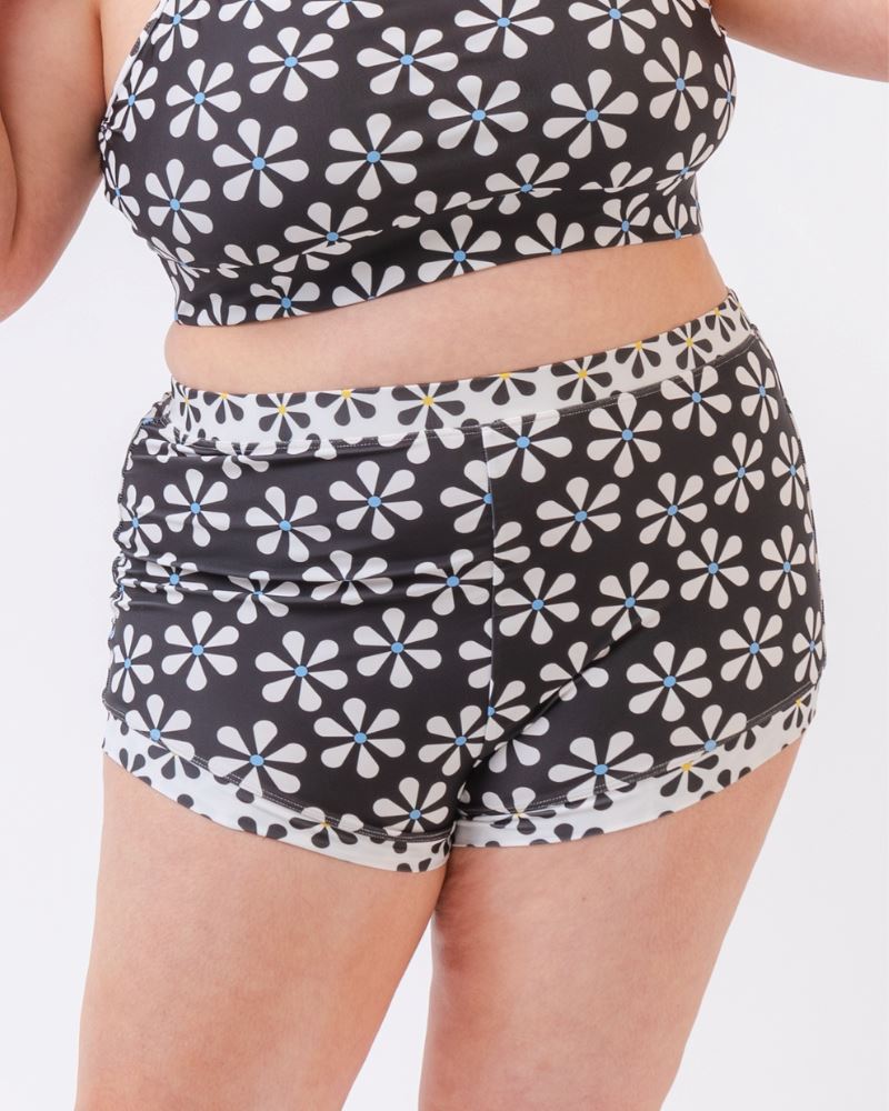 Close-up photo of a woman wearing a black and white floral swim short bottom and a black and white floral swim bralette
