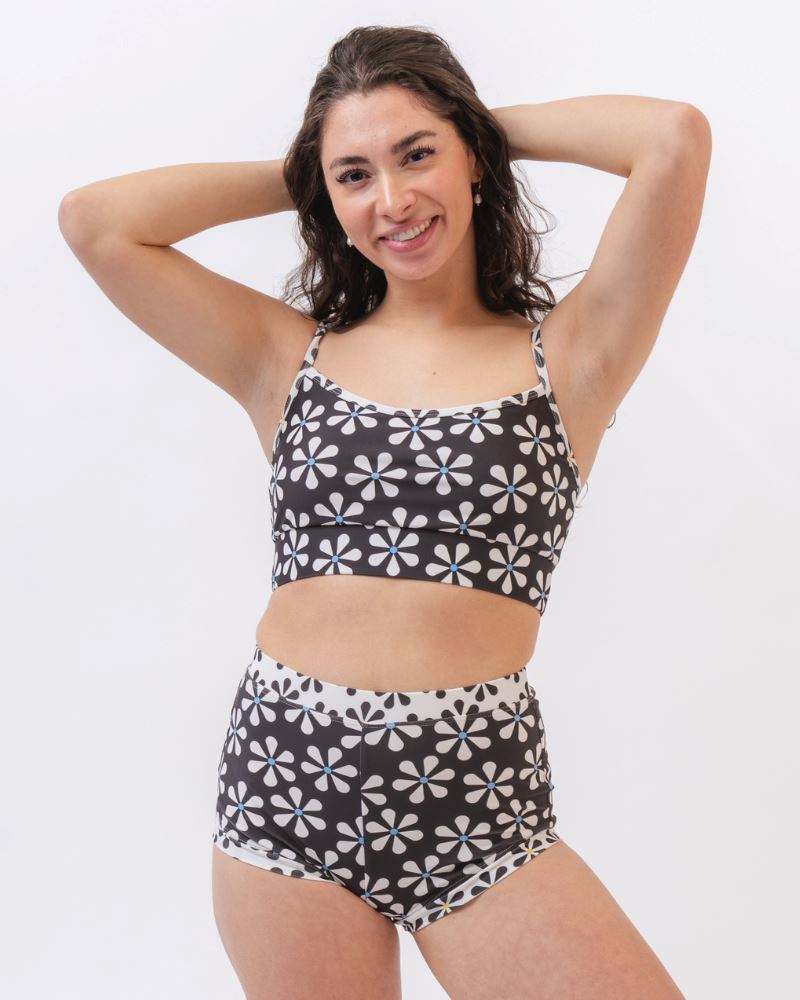 Photo of a woman wearing a black and white floral swim bralette and a black and white floral swim short bottom