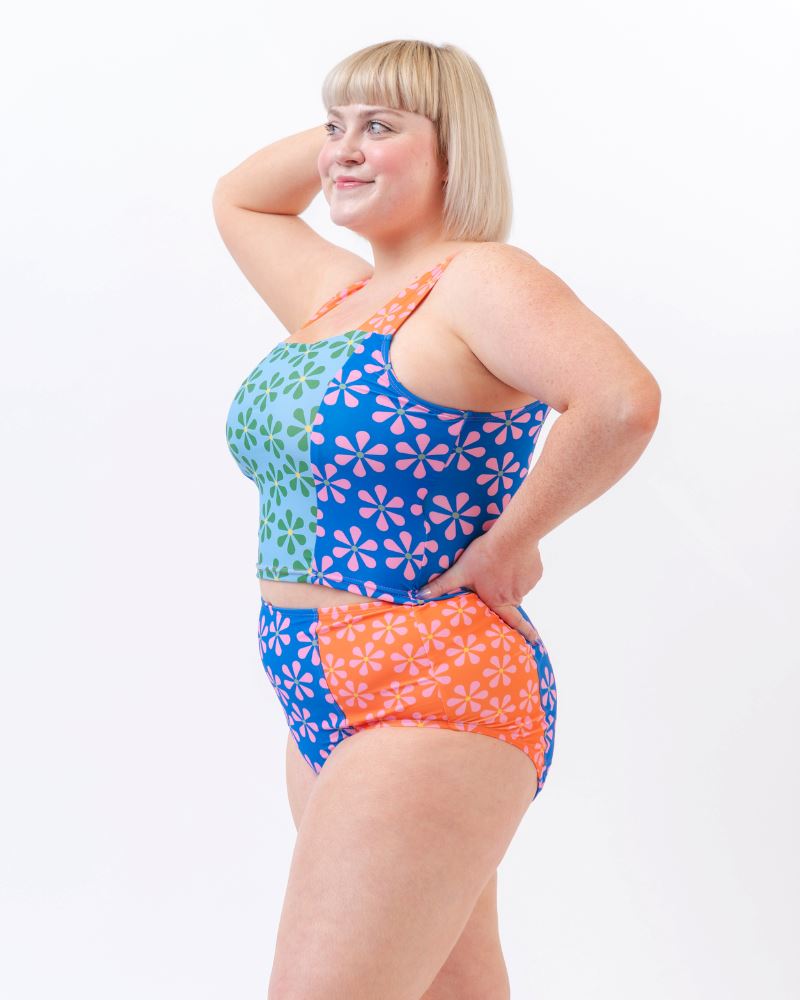 Photo of a woman wearing a multi-colored floral high-waist swim bottom and a multi-colored floral swim crop top- side angle