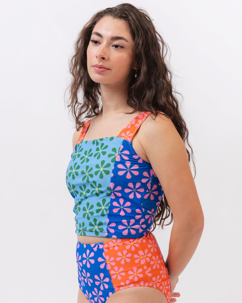 Photo of a woman wearing a multi-colored floral high-waist swim bottom and a multi-colored floral swim crop top- side angle