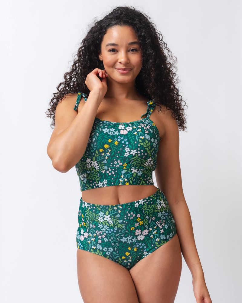 Photo of a woman wearing a dark green floral/ light green reversible swim bottom - floral side and a dark green floral shoulder-tie swim crop top