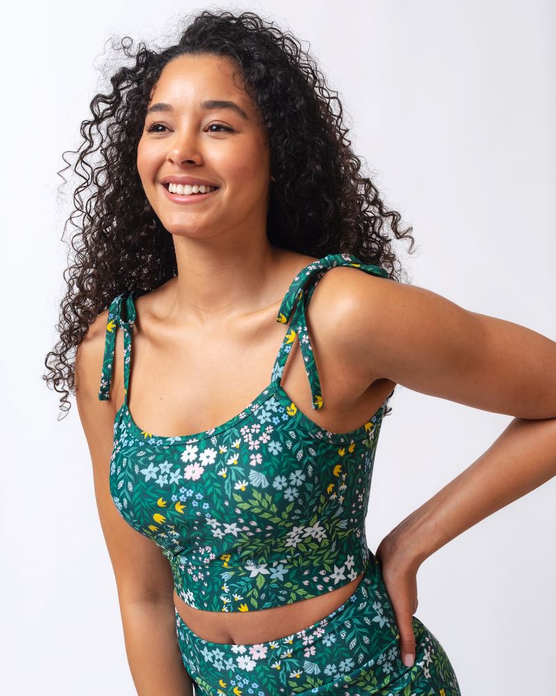 Close up photo of a woman wearing a dark green floral shoulder-tie swim crop top
