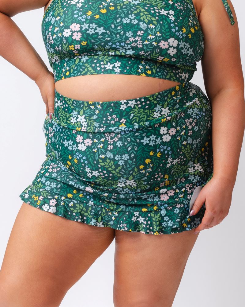 Close up photo of a woman wearing a dark green floral swim skirt
