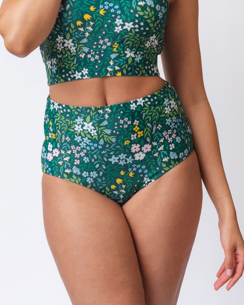 Close up photo of a woman wearing a dark green floral/ light green reversible swim bottom - floral side