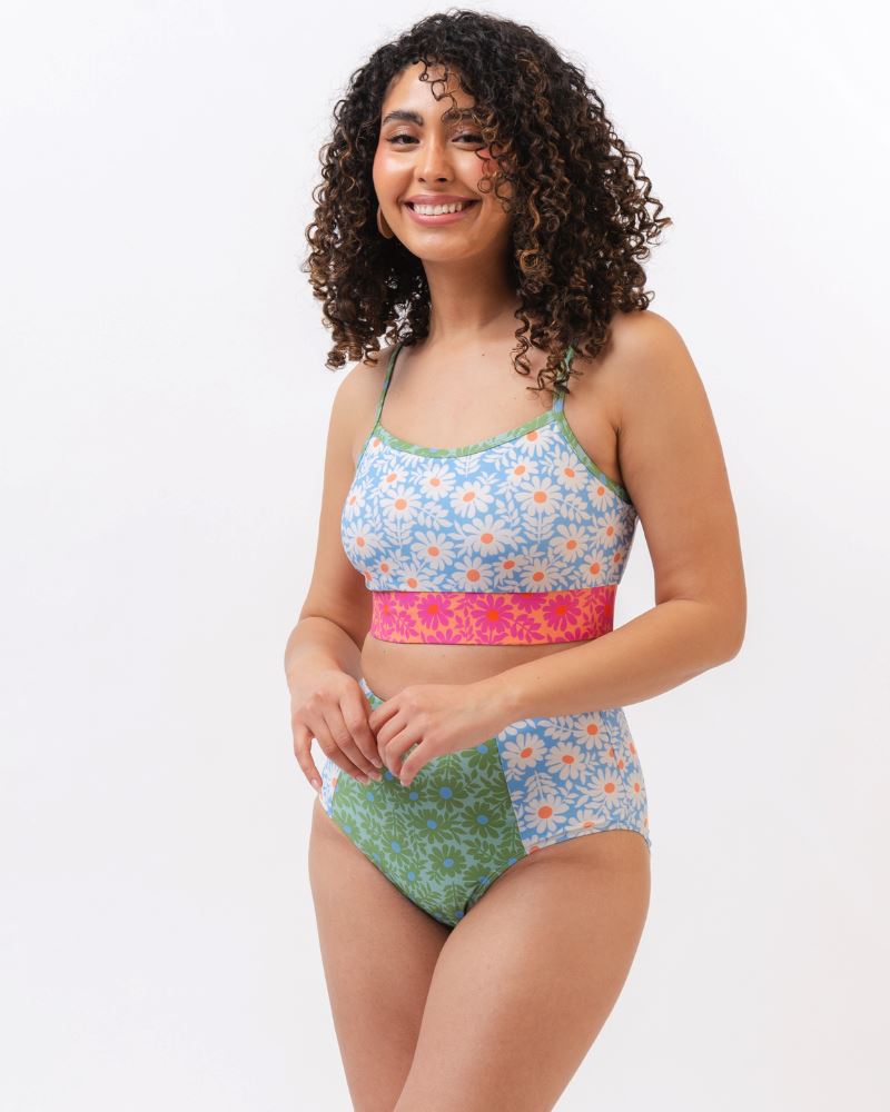 Photo of a woman wearing a blue and pink floral cropped swim top with blue and green floral high waist swim bottoms